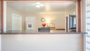 A hotel reception area with a marble counter, a clock, a framed picture, a vase with flowers, and a television. - The Hillside Hotel (Knoxville)