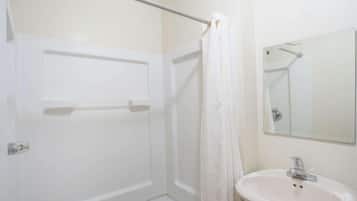 A bathroom with a shower, a sink, and a mirror.
