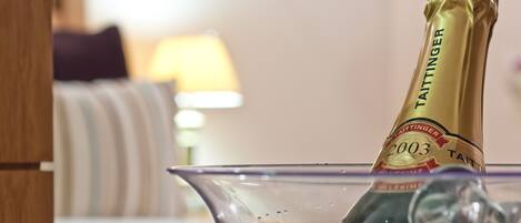 A champagne bottle labeled 'Taittinger 2003' in a glass bowl with ice cubes.