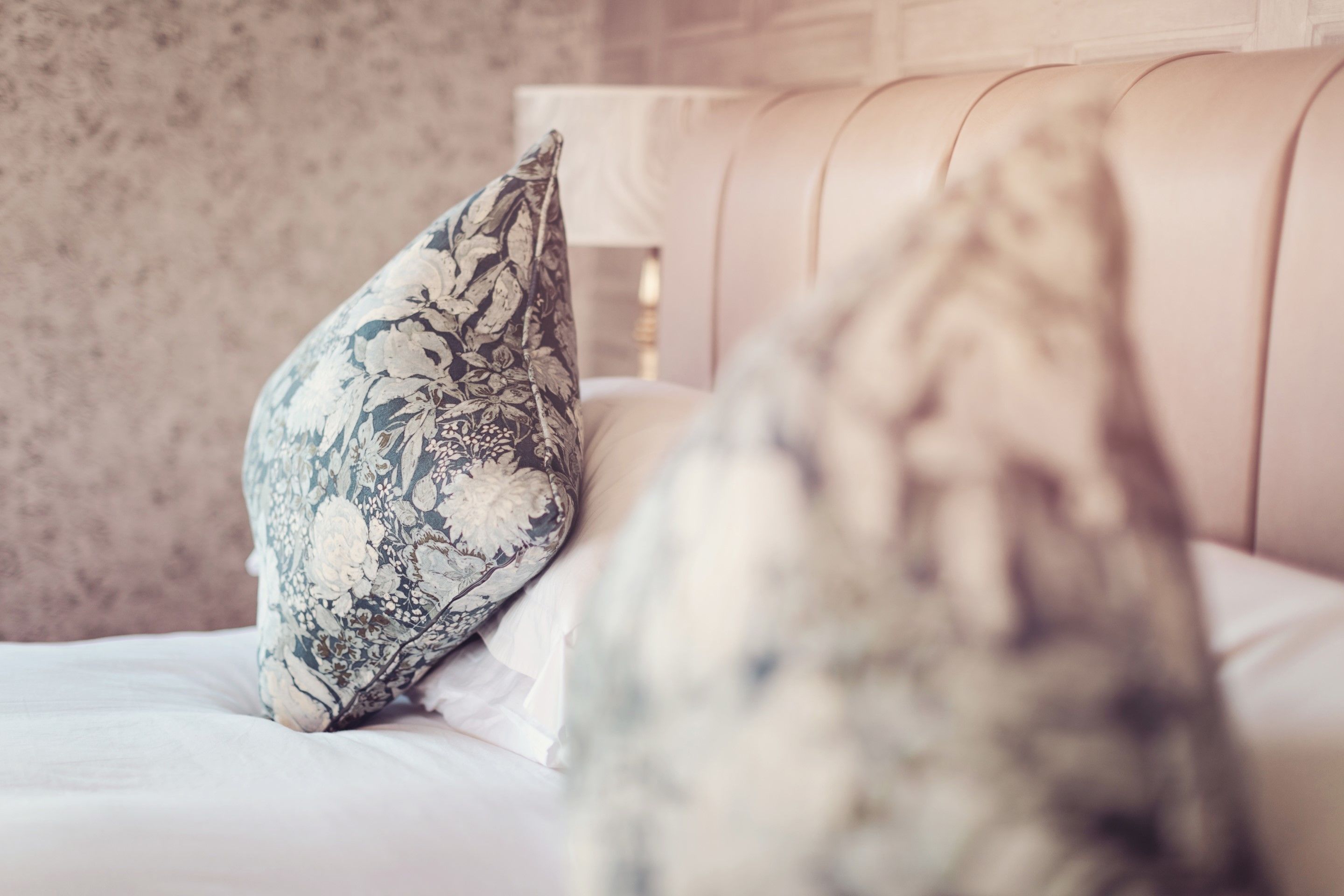 A bed with a floral-patterned pillow and a plain pillow.