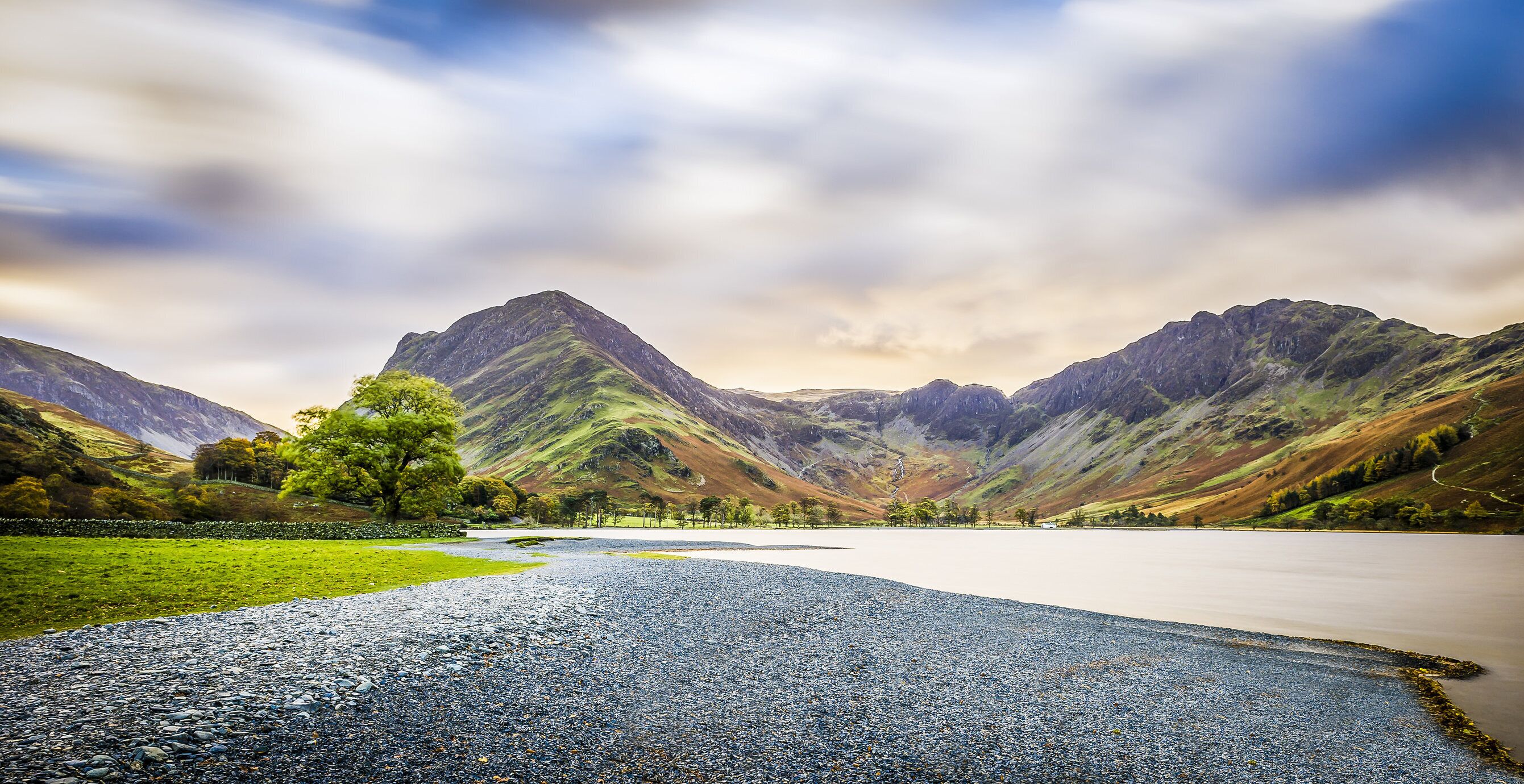 A mountainous landscape with a lake and a gravel path.
