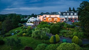 A large, multi-story building with a well-maintained garden and a driveway. - Windermere Hillthwaite Hotel (Windermere)