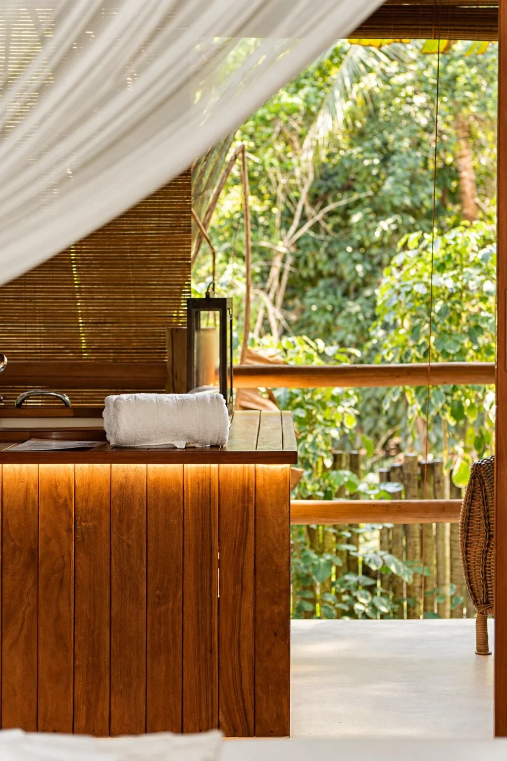Uma área de spa em madeira com um banco, uma toalha e um candeeiro.