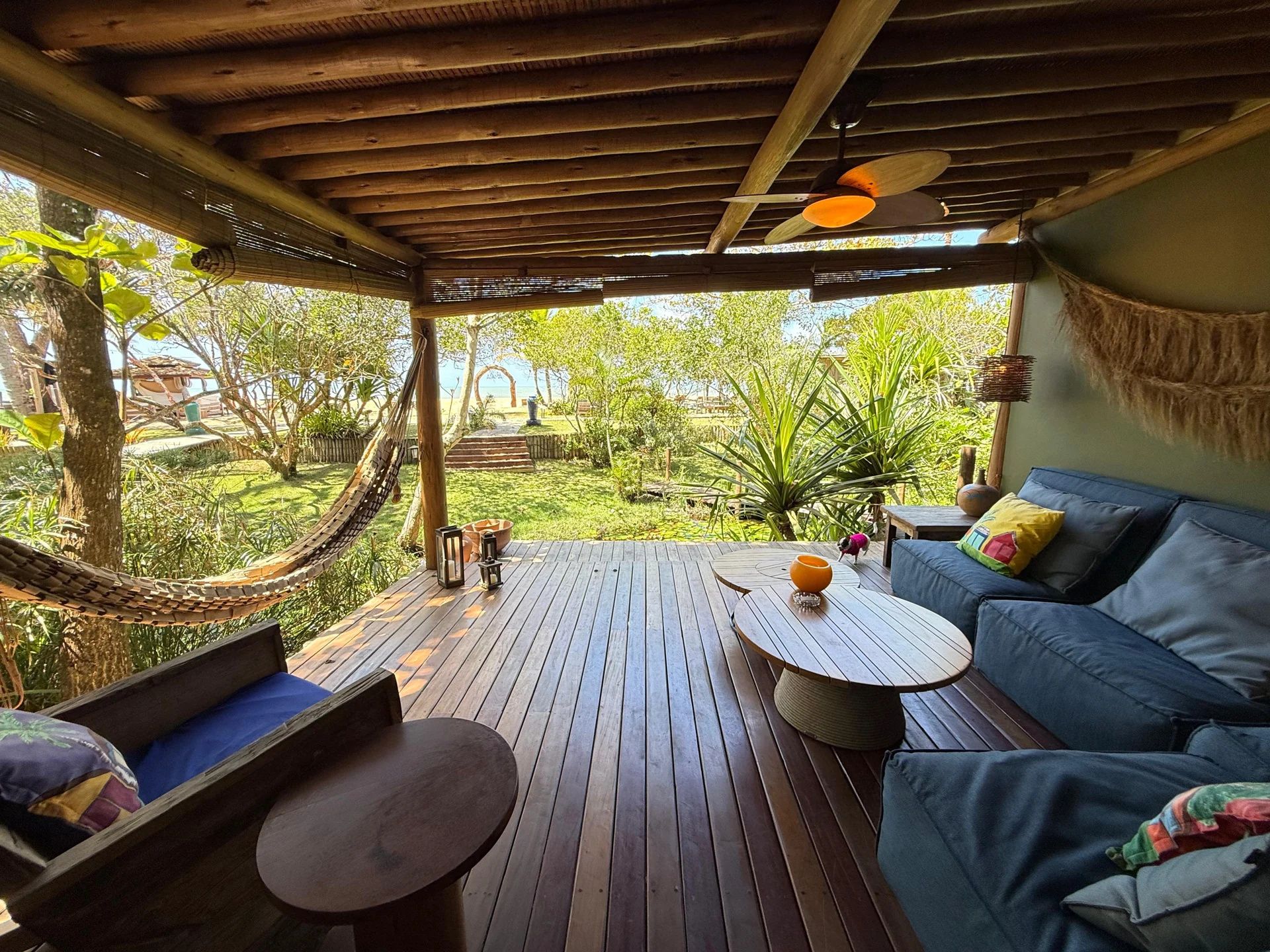 A wooden deck with a hammock, a sofa, and a table.
