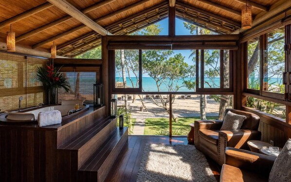 Un interior de madera con un amplio ventanal con vista a una playa.