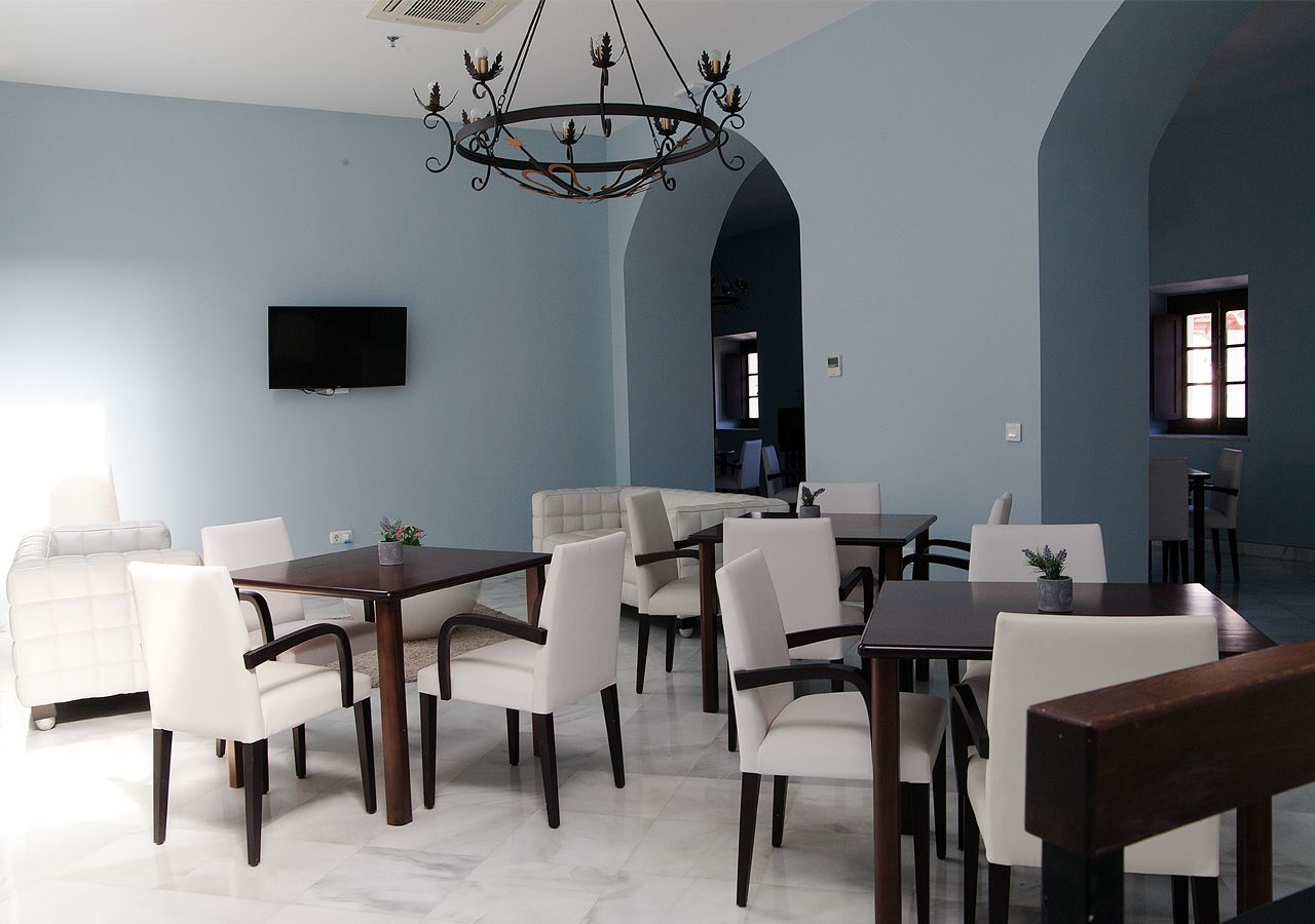 A dining area with a large table and chairs, a chandelier, and a TV mounted on the wall.
