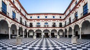 A courtyard with a checkered floor, white columns, and balconies. - Hotel Boutique Convento Cádiz (Cádiz)