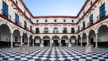 Un patio con suelo a cuadros, columnas blancas y balcones.