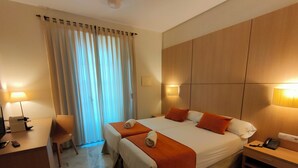 A hotel room with a double bed, two bedside tables, a desk with a chair, a lamp, and a window with curtains. - Hotel Boutique Convento Cádiz (Cádiz)