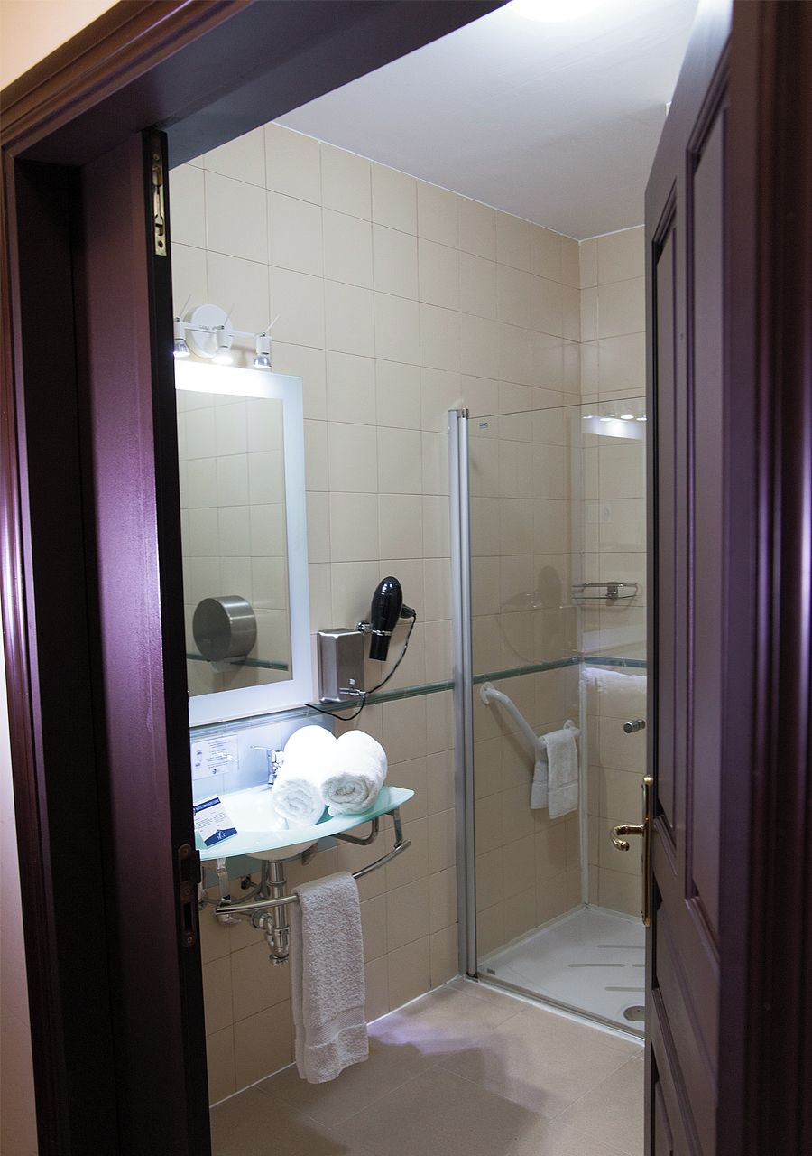A bathroom with a glass shower enclosure, a sink with a towel rack, and a mirror.