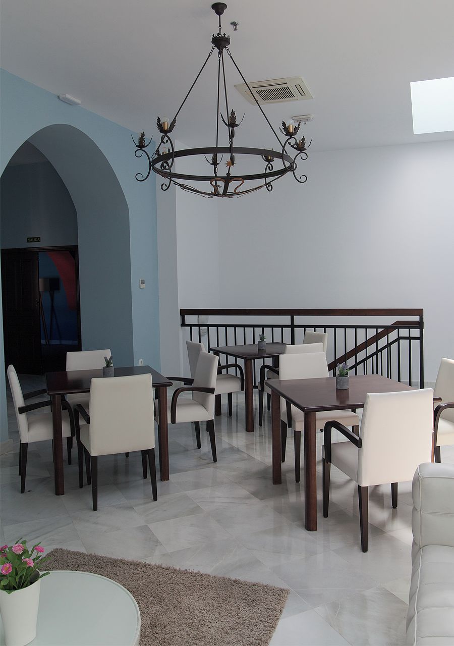 Ein Essbereich mit einer Chandelier, weißen Stühlen und einer Treppe.
