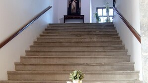 A staircase with a table and chairs in the foreground, leading to a room with a painting on the wall. - Hotel Boutique Convento Cádiz (Cádiz)
