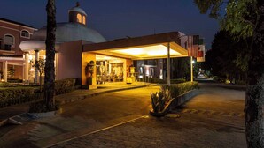 A hotel entrance with a covered outdoor area, a dome-shaped building, and a flag. - MM Grand Hotel Puebla, Tapestry Collection by Hilton (Puebla)