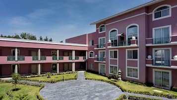 Un hotel de varios pisos con un patio central, balcones y un jardín bien cuidado.