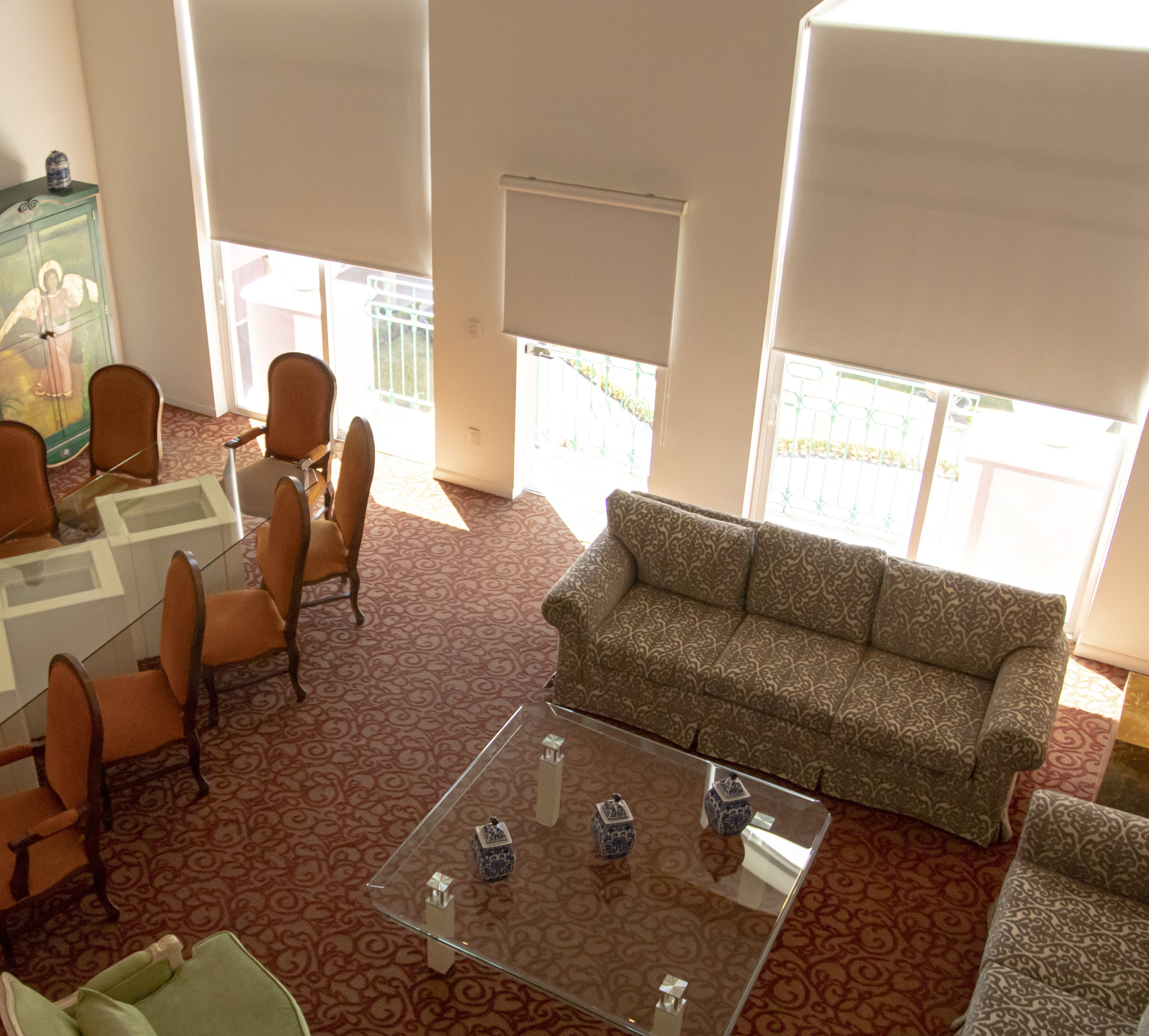 A spacious living room with a patterned carpet, a sofa, armchairs, and a glass coffee table.