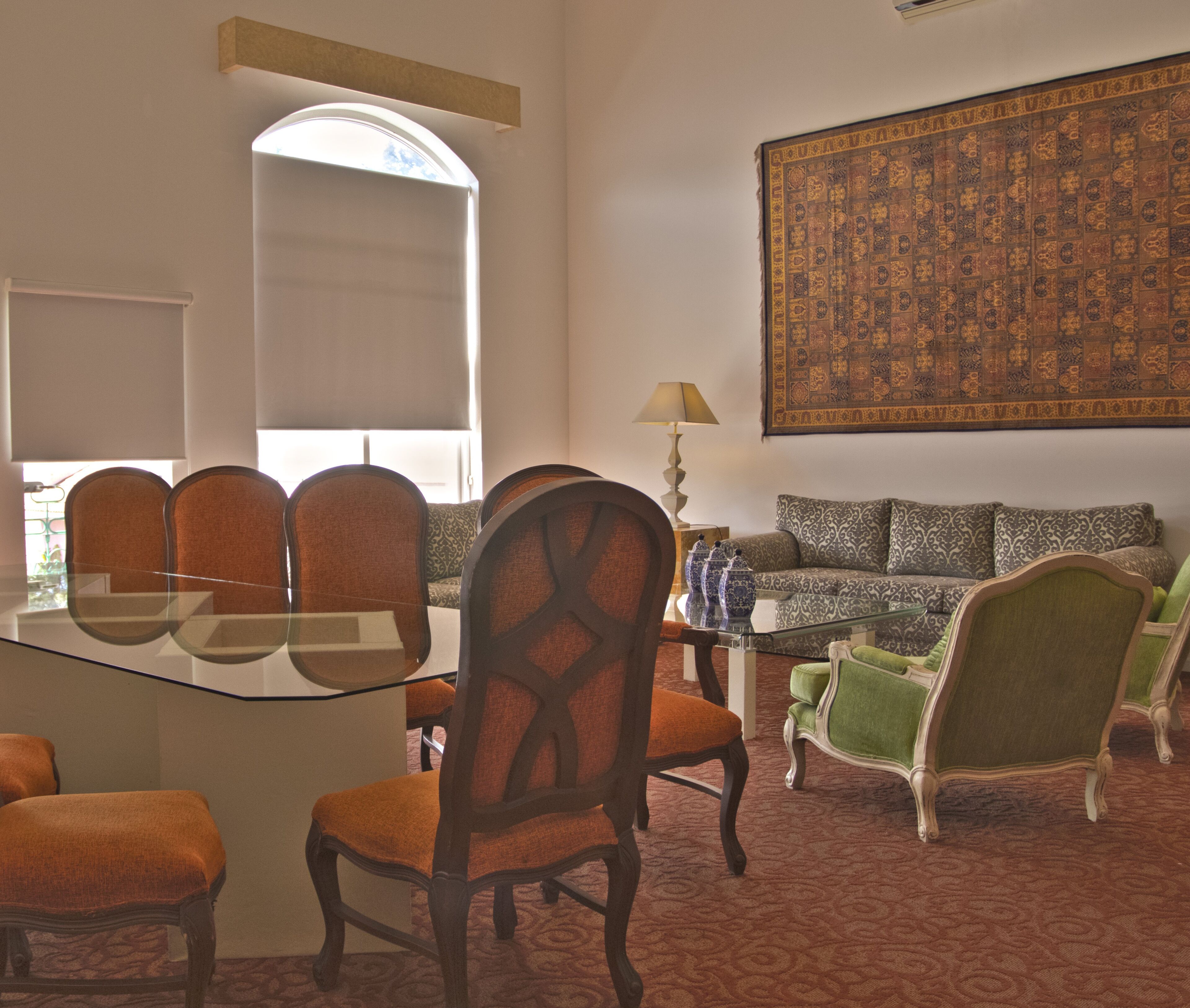 Una habitación con una mesa de comedor, sillas, un sofá y un gran tapiz decorativo en la pared.
