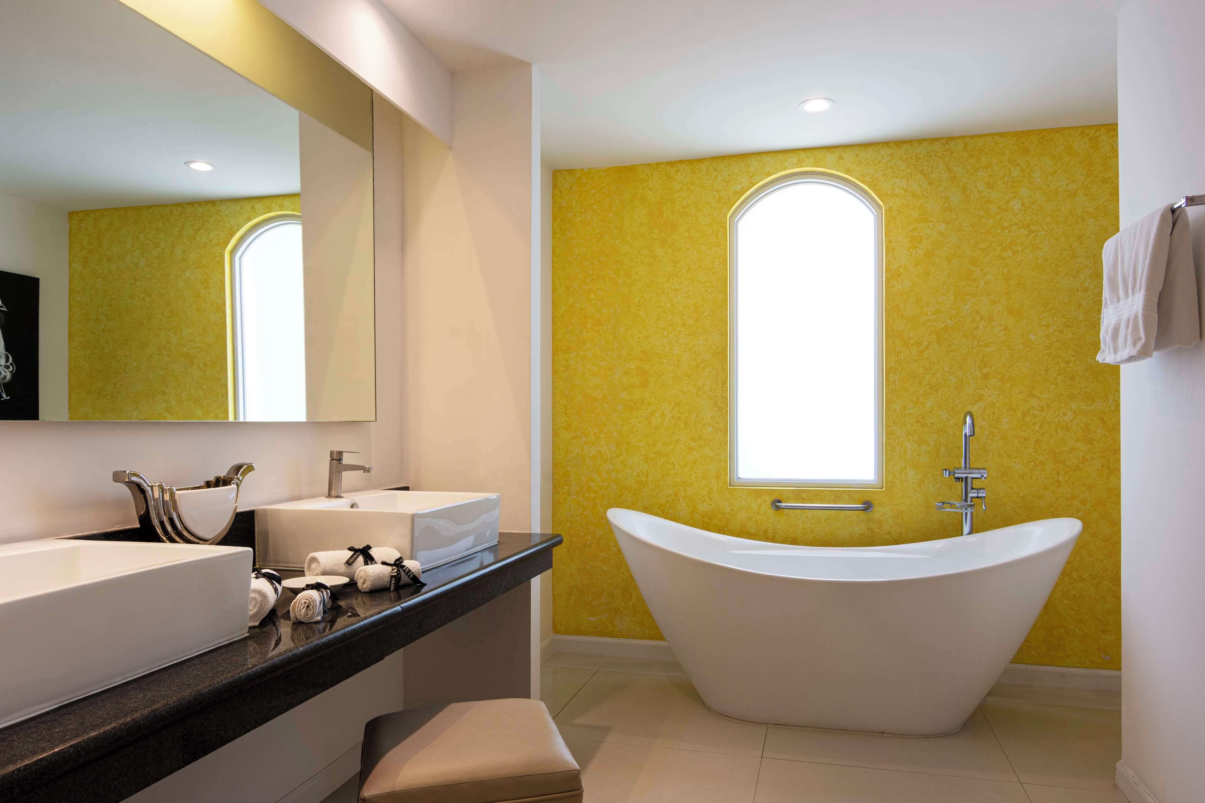 A modern bathroom with a freestanding bathtub, a large mirror, and a vanity with a sink and towel rack.