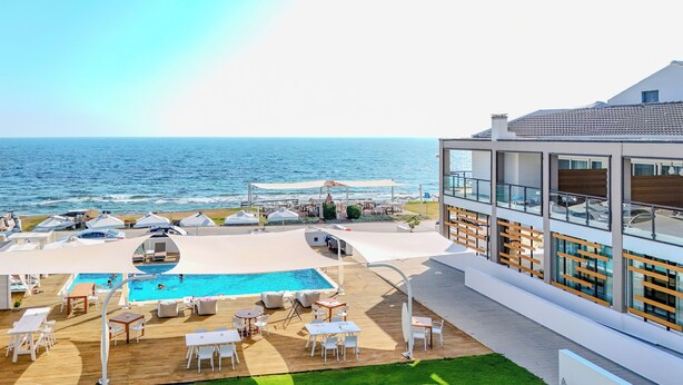 A rooftop pool area with lounge chairs and umbrellas, overlooking the sea. - Sesa Boutique Hotel (Preveza)