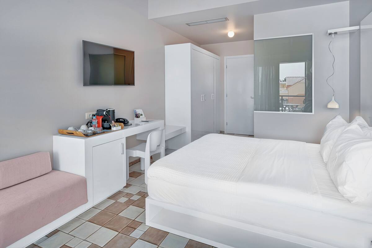 A modern bedroom with a bed, a desk, a chair, a wardrobe, and a mirror.
