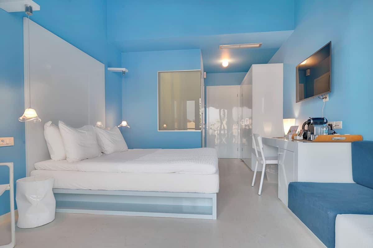 A modern bedroom with a bed, bedside table, and a desk area with a chair.