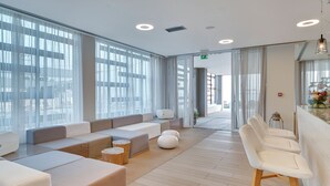 A modern hotel lobby with a seating area, large windows, and a bar. - Sesa Boutique Hotel (Preveza)