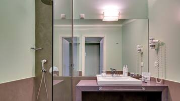 A modern bathroom with a glass-enclosed shower, a sink with toiletries, and a mirror.
