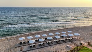 A beach with rows of sun loungers and umbrellas, a wooden deck, and a view of the ocean. - Sesa Boutique Hotel (Preveza)