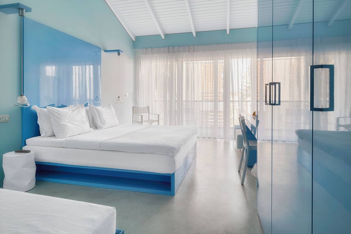A modern bedroom with a large bed, a bedside table, a chair, and a glass partition.