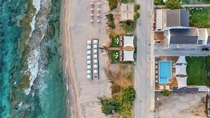 An aerial view of a beachside property with a swimming pool, umbrellas, and lounge chairs. - Sesa Boutique Hotel (Preveza)