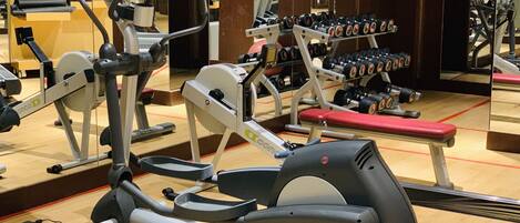 A gym with various exercise equipment including treadmills, weight machines, and dumbbells.
