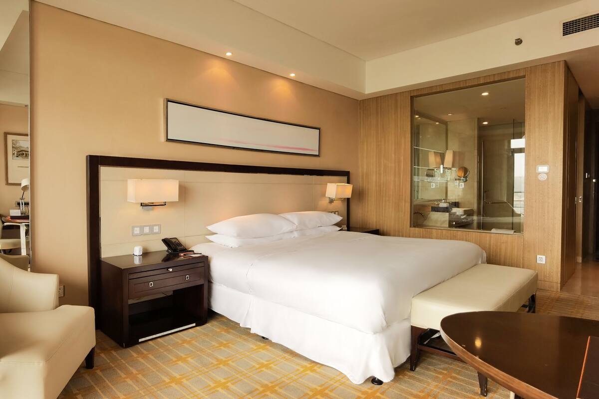 Une chambre d’hôtel avec un grand lit, des tables de chevet, un bureau et un coin salon.