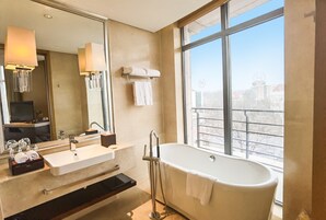 Un baño moderno con un ventanal grande, una bañera, un lavabo y un espejo.