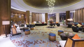 A spacious lobby with multiple seating areas, a decorative ceiling, and a large window providing natural light. - Sheraton Qinhuangdao Beidaihe Hotel (Qinhuangdao)