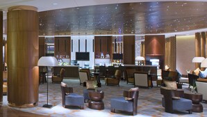A modern lobby with a bar area, seating arrangements, and a large pillar. - Sheraton Qinhuangdao Beidaihe Hotel (Qinhuangdao)
