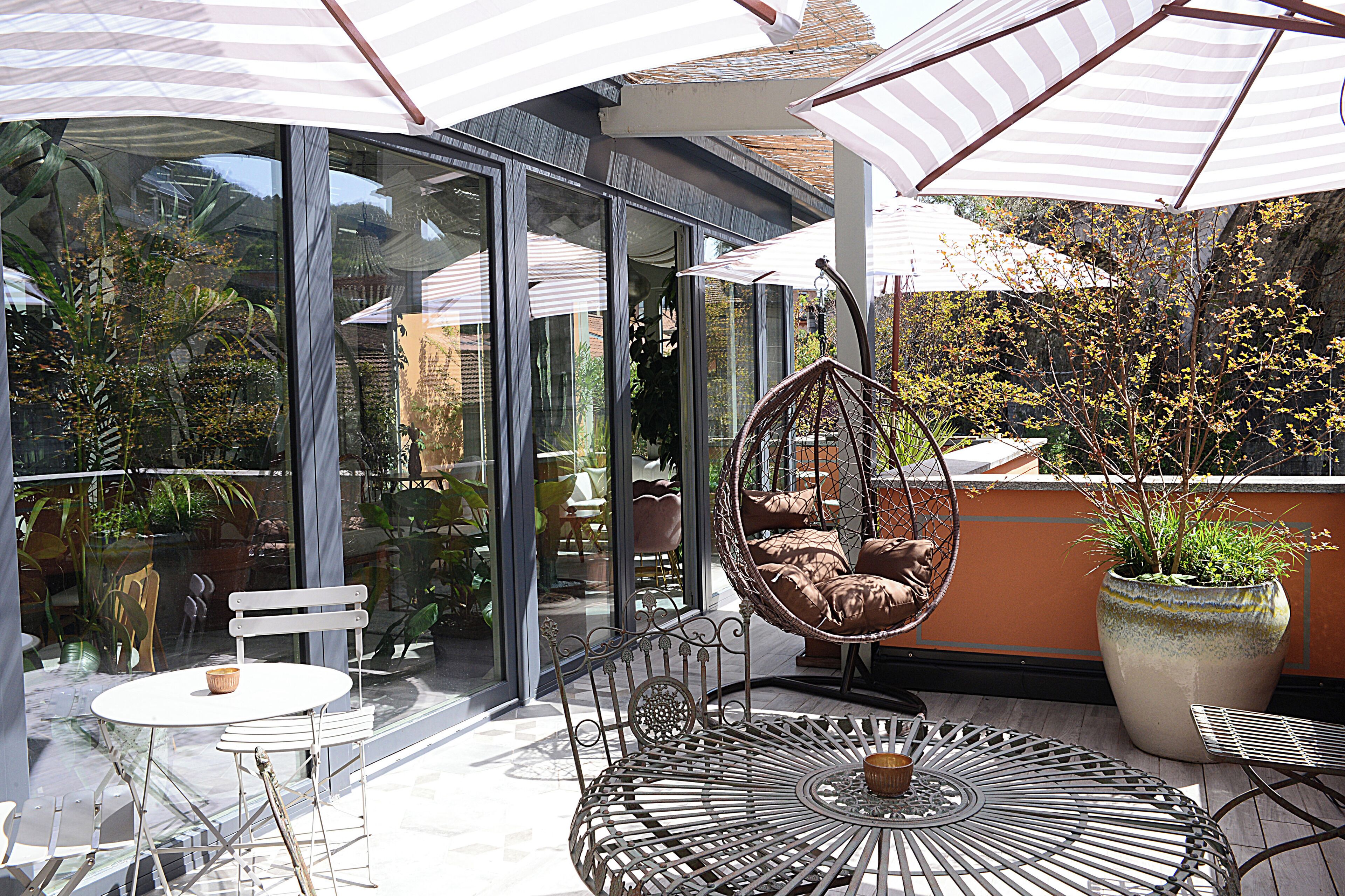 A glass-enclosed patio with outdoor furniture, including a hanging chair and a round table.