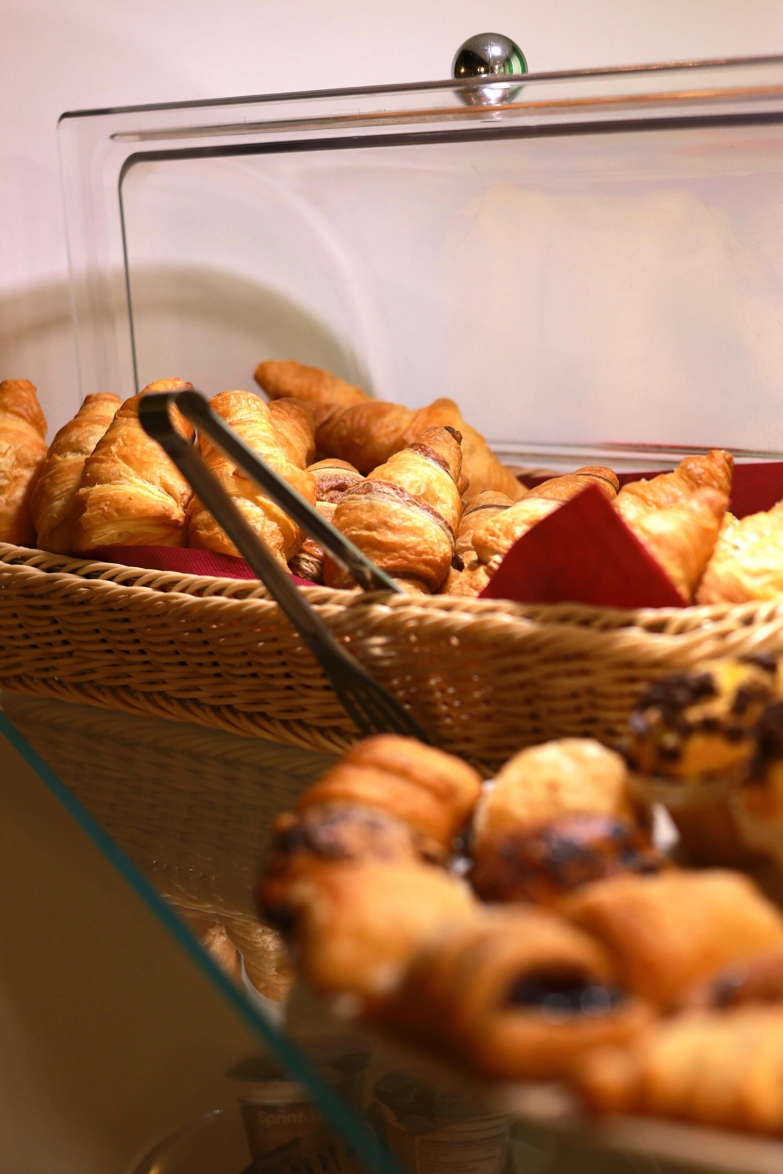 Een vitrine met diverse gebakjes, waaronder croissants en ander vers gebak.