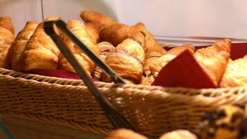 Een vitrine met diverse gebakjes, waaronder croissants en ander vers gebak.