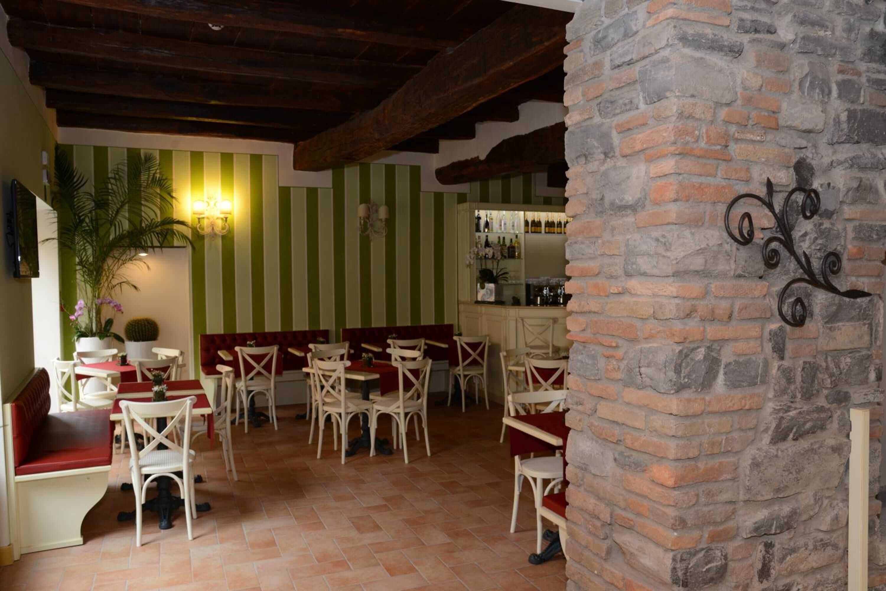Un restaurante con paredes a rayas, vigas de madera y pilares de ladrillo. Mesas y sillas dispuestas para comer.