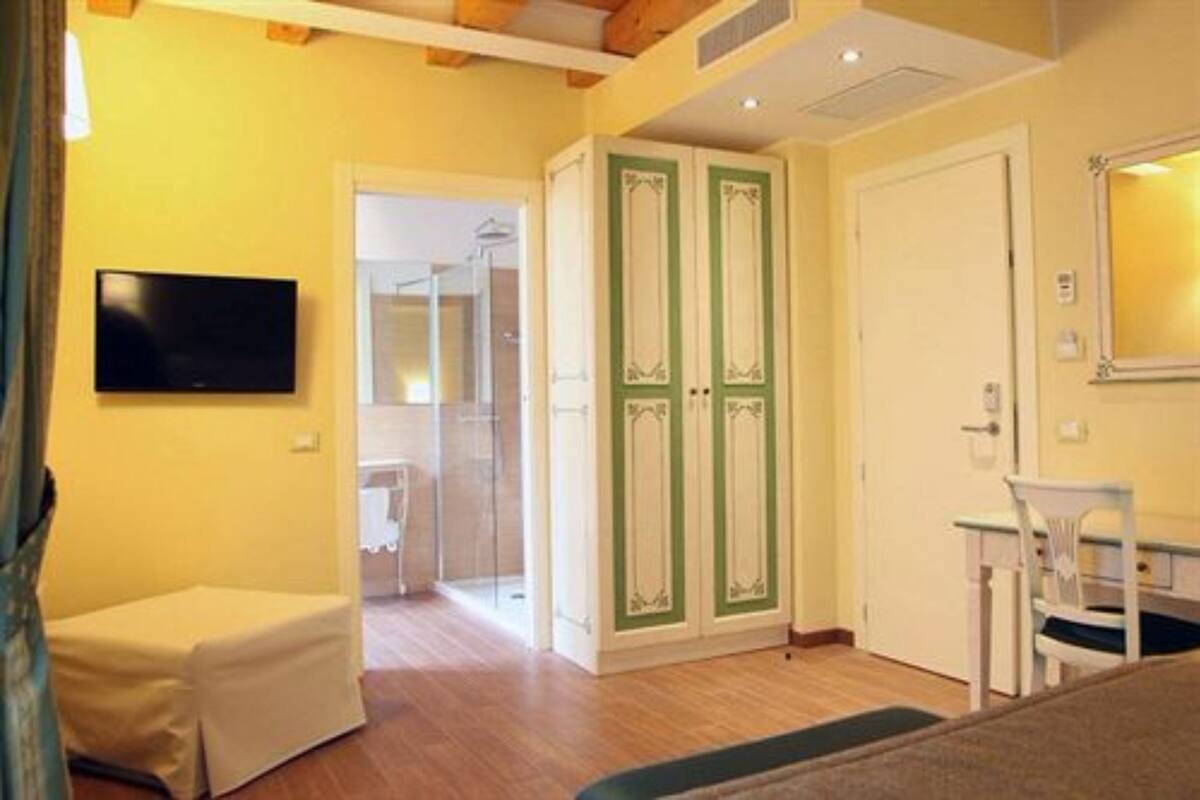 Una habitación con televisión, una mesita, una silla y un armario con puertas verdes.