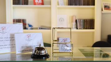 Una mesa de recepción con un timbre, una vitrina de cristal con una tarjeta, y varias tarjetas informativas.