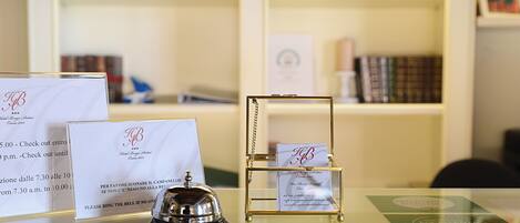 A reception desk with a bell, a glass display case with a card, and several informational cards.