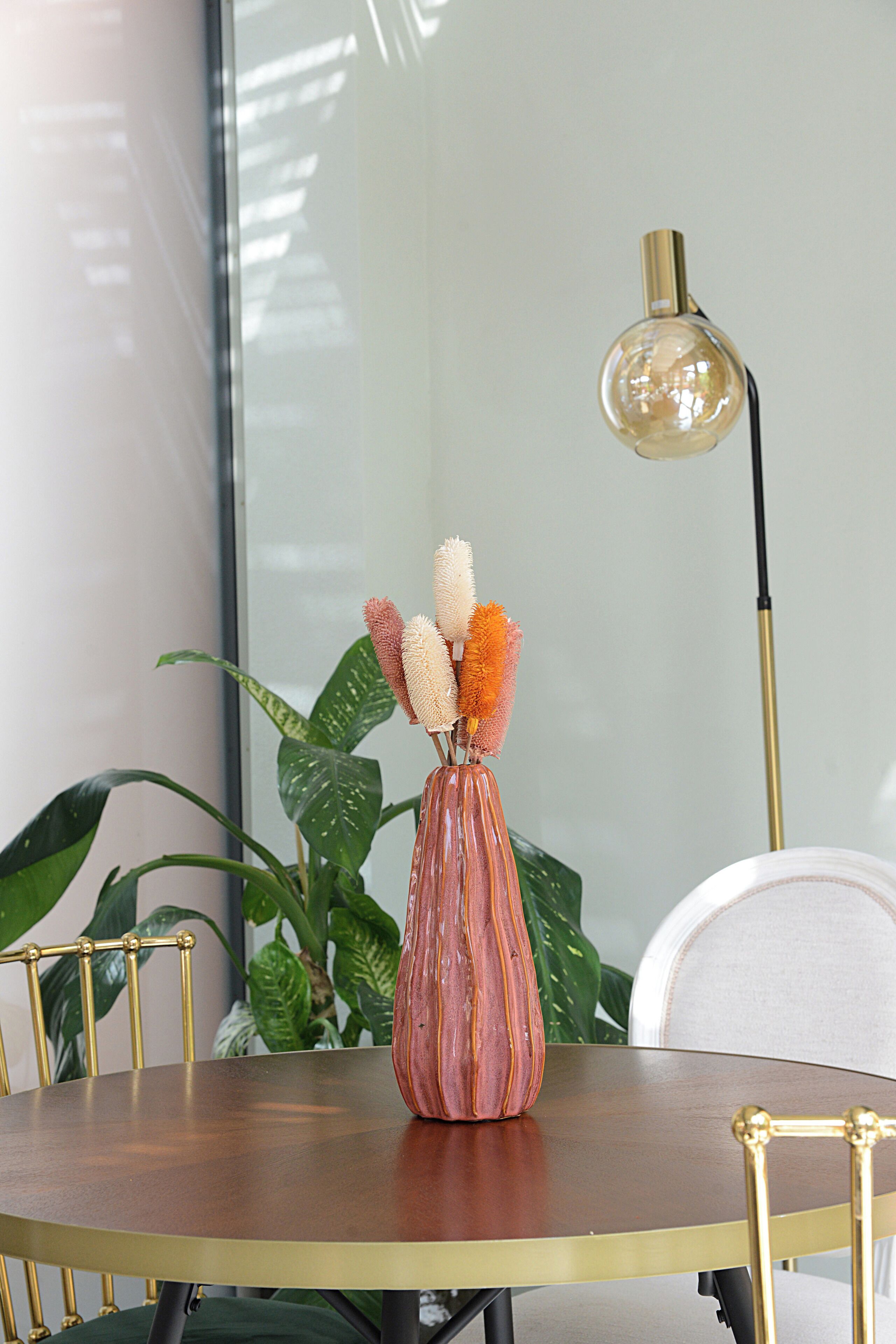 Ein runder Tisch mit Blumen, einer Lampe und Stühlen.