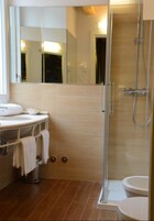 Un baño moderno con ducha de vidrio, lavamanos con espejo e inodoro.