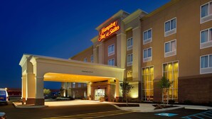 Un hôtel Hampton Inn & Suites avec une entrée bien visible, un espace de stationnement couvert et une façade en briques.