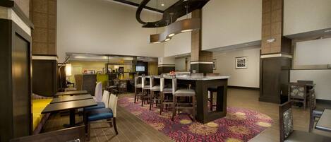 A hotel lobby with a central island, multiple seating areas, and a patterned carpet.