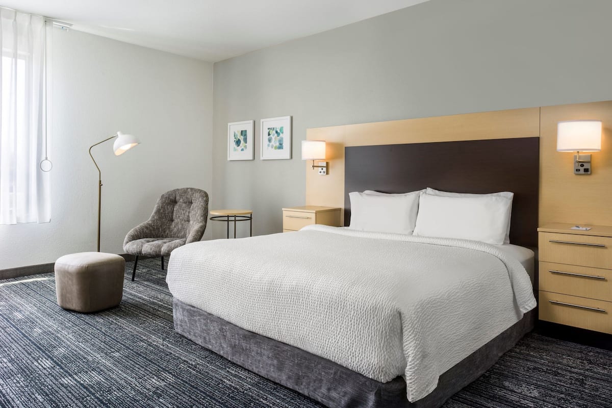 Een hotelkamer met een groot bed, een stoel, een bureau en een lamp.