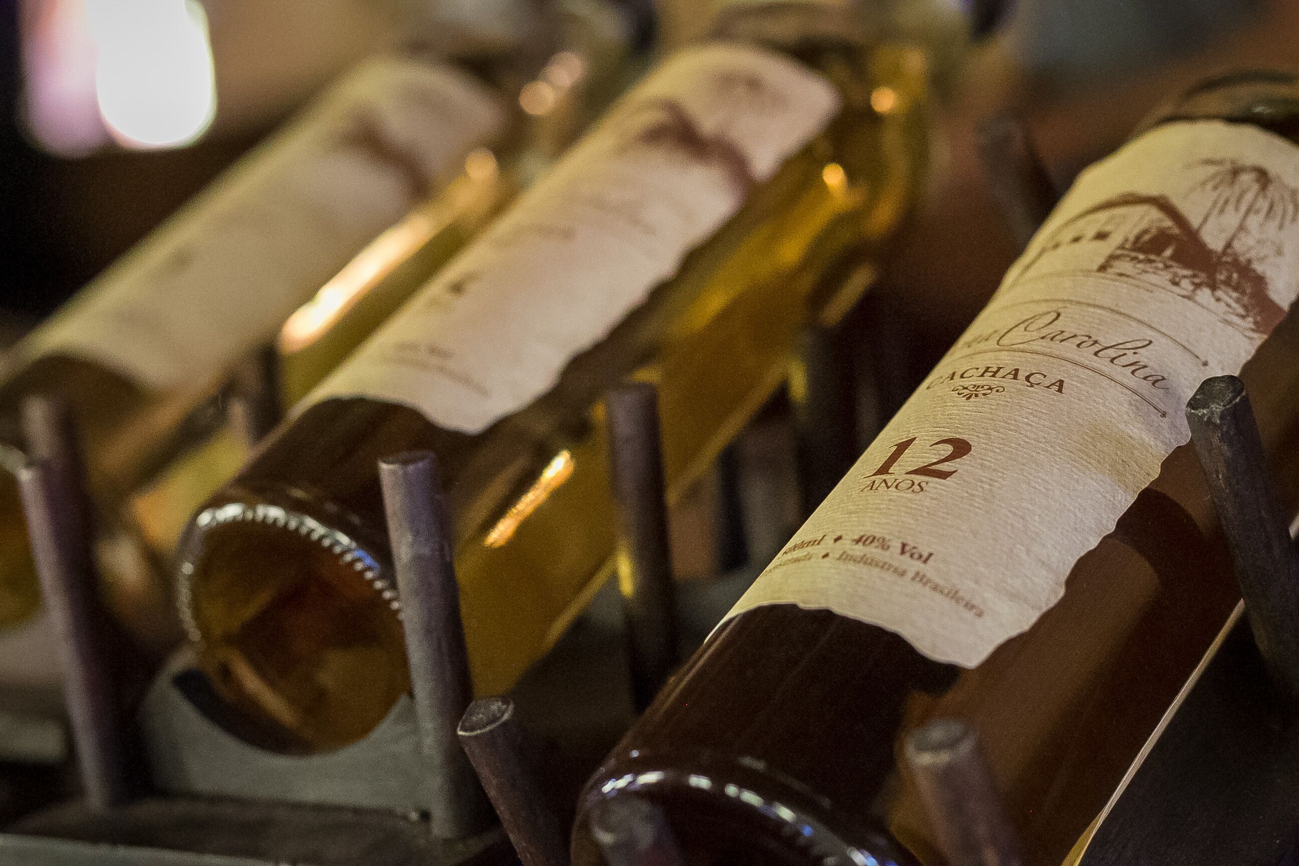Um primeiro plano de garrafas de vinho com etiquetas, incluindo uma com a etiqueta 'Carolina' e '12 ANOS'.
