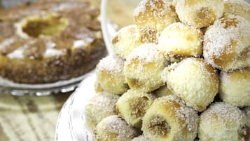 Um prato com bolinhos redondos cobertos de coco e um bolo com um buraco no centro.
