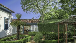 Un jardín bien cuidado con un sendero que lleva a un edificio de paredes blancas y tejado de tejas.