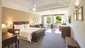 Habitación de hotel con una cama grande, un escritorio, una silla, una mesita y vistas al exterior.